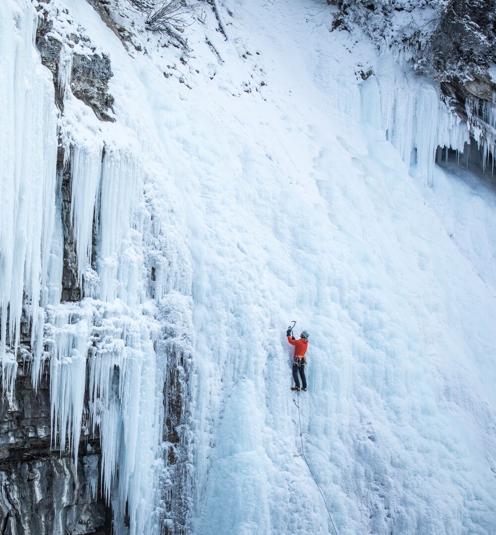 Person ice climbing on the frozen falls of Johnston Canyon
